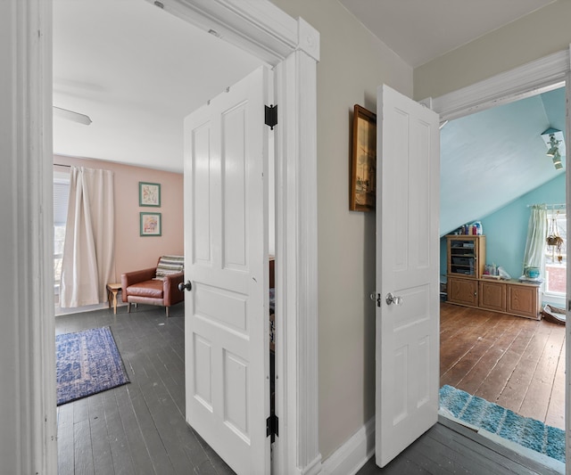 hallway featuring hardwood / wood-style flooring, baseboards, and lofted ceiling