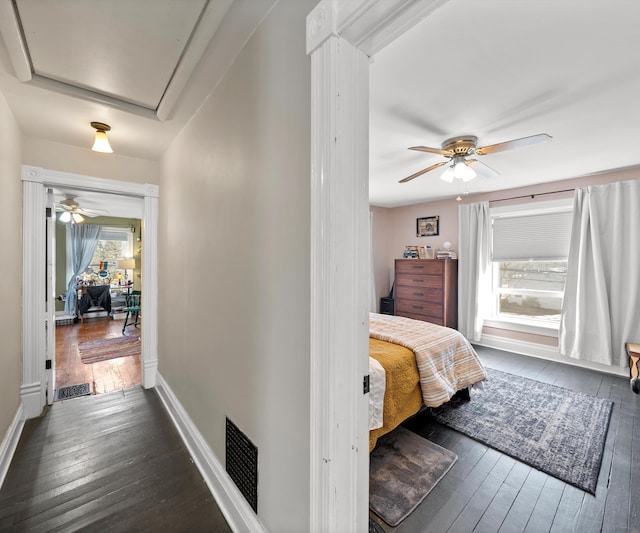 hall with dark wood-type flooring, baseboards, and visible vents