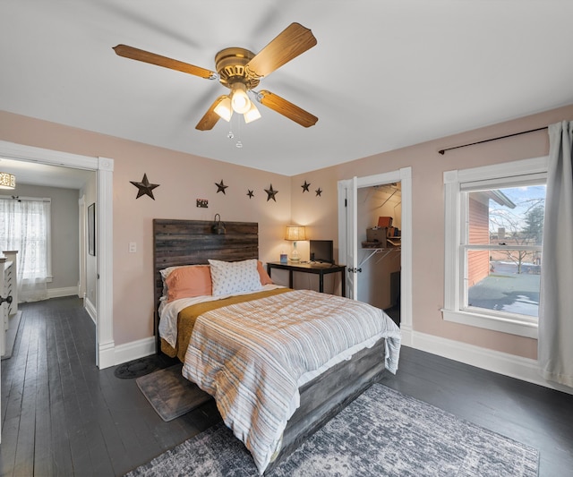 bedroom featuring baseboards, multiple windows, a spacious closet, and hardwood / wood-style flooring