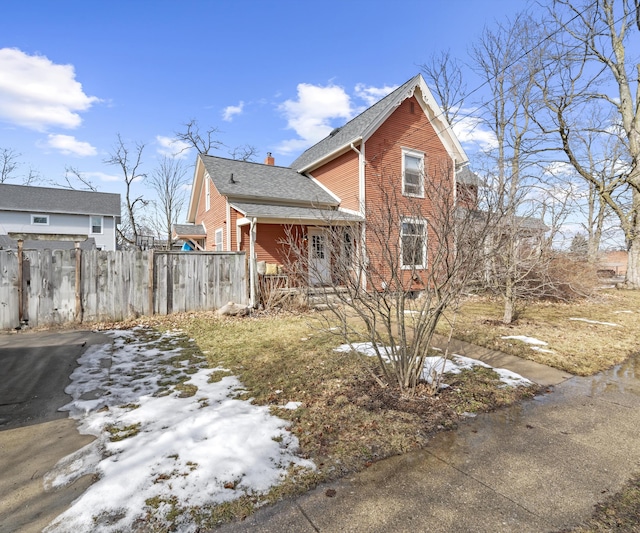 view of front of home featuring a chimney, roof with shingles, and fence