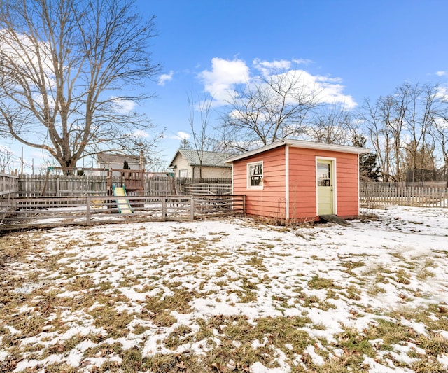 yard covered in snow featuring an outbuilding, a playground, and fence