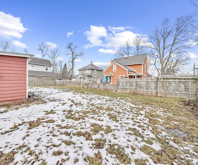 yard covered in snow with a residential view and fence