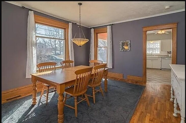 dining area featuring crown molding, baseboards, and wood finished floors