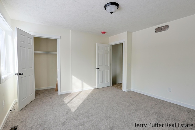 unfurnished bedroom with baseboards, carpet floors, a textured ceiling, and a closet