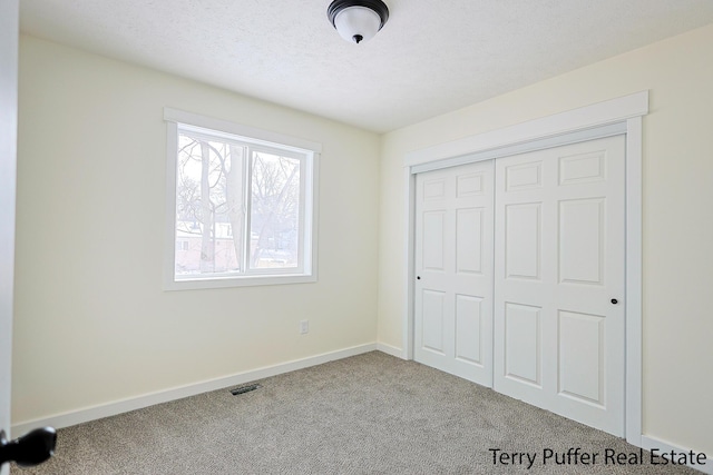 unfurnished bedroom featuring a closet, baseboards, carpet, and a textured ceiling