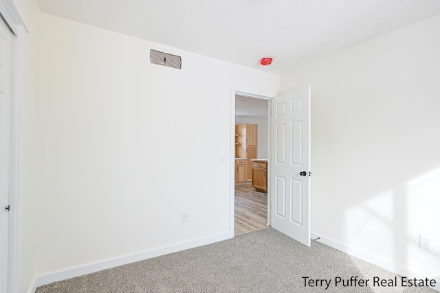 unfurnished bedroom with light colored carpet and baseboards