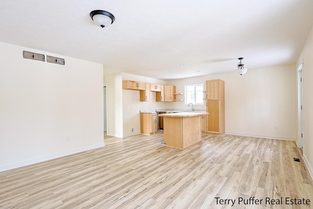 kitchen with light wood-type flooring, light brown cabinetry, a center island, and a sink