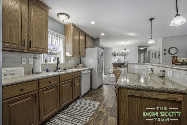 kitchen featuring white appliances, a sink, dark wood-type flooring, decorative light fixtures, and tasteful backsplash