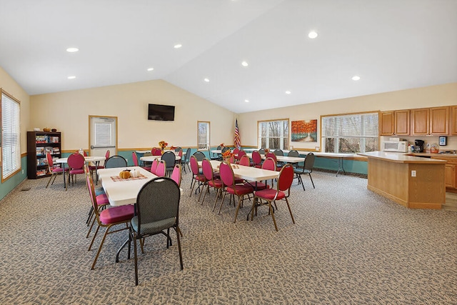 dining room with light colored carpet, a healthy amount of sunlight, and vaulted ceiling