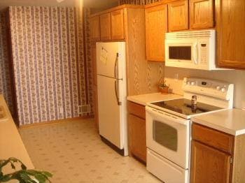 kitchen featuring brown cabinets, white appliances, and light countertops