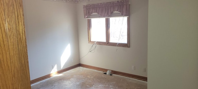 unfurnished room with baseboards and concrete floors