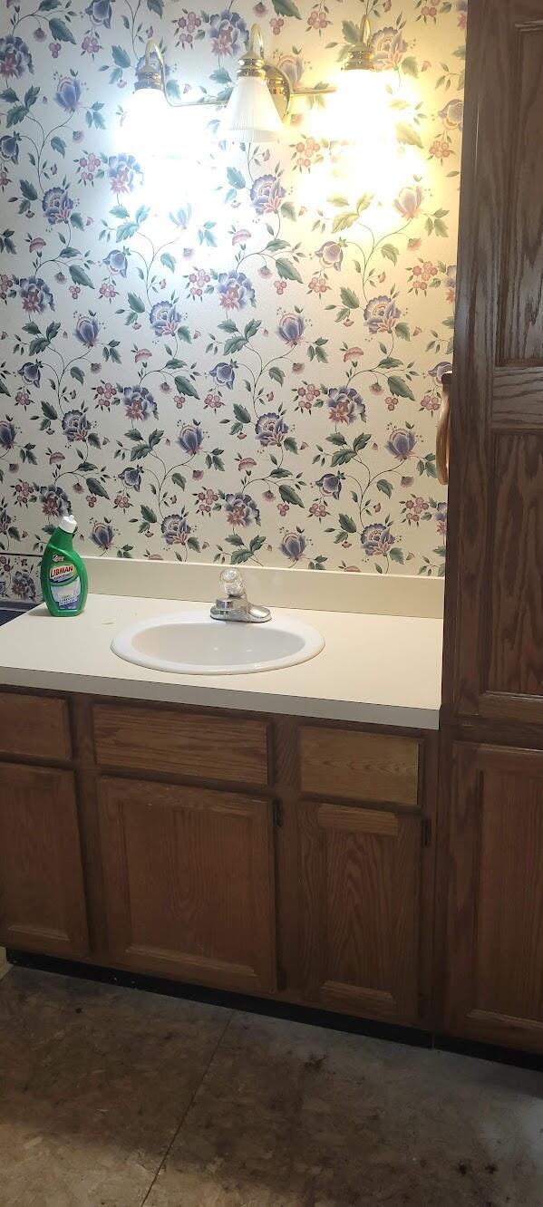 bathroom featuring vanity and wallpapered walls