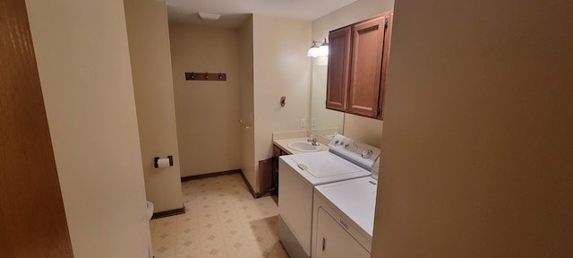 clothes washing area featuring a sink, washing machine and dryer, cabinet space, baseboards, and light floors