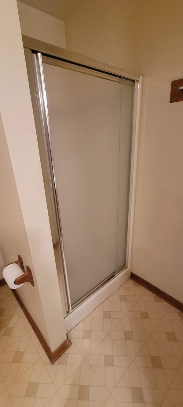 bathroom with tile patterned floors, a shower stall, and baseboards