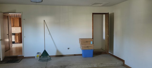 unfurnished bedroom featuring visible vents, baseboards, concrete flooring, and attic access