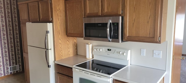 kitchen with white appliances, brown cabinetry, light countertops, and visible vents