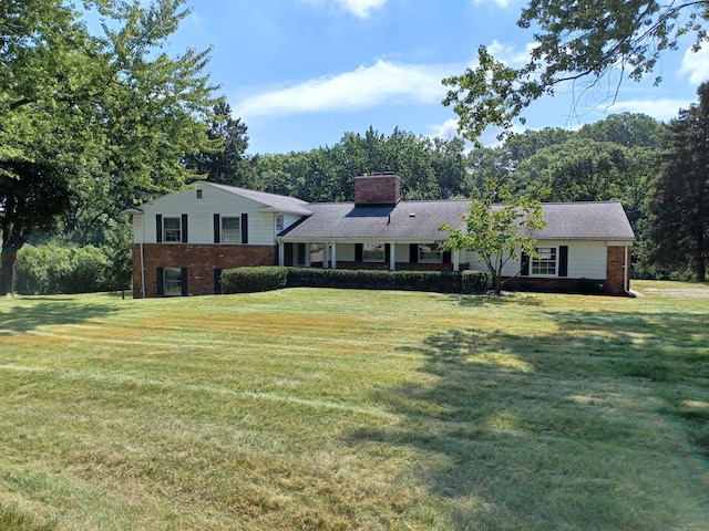 split level home with brick siding, a chimney, and a front lawn