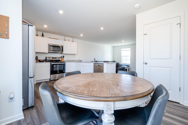 dining room featuring dark wood-type flooring, recessed lighting, and baseboards