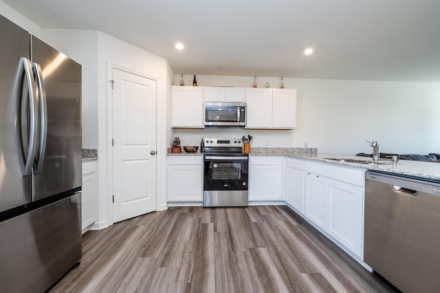 kitchen with a sink, wood finished floors, white cabinetry, and stainless steel appliances