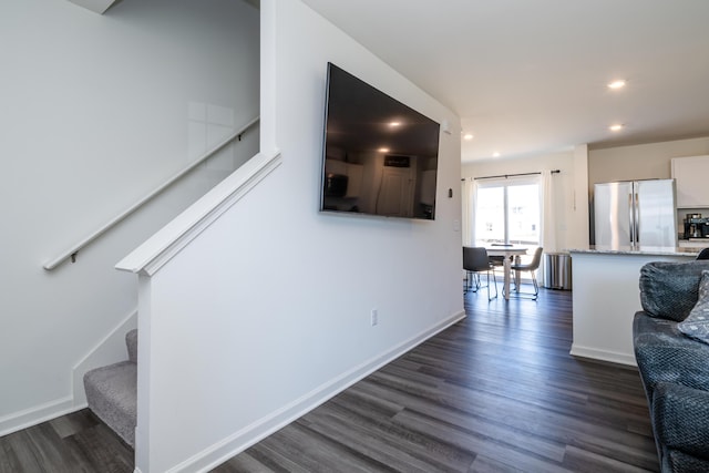 hallway featuring stairs, dark wood-type flooring, and baseboards