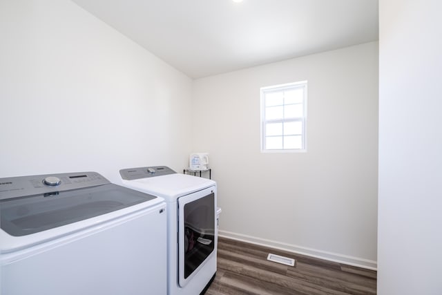 washroom featuring visible vents, baseboards, dark wood finished floors, washing machine and dryer, and laundry area