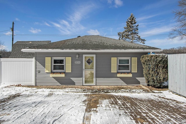 view of front of home with a shingled roof and fence