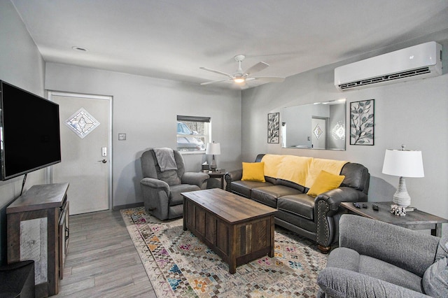 living room featuring a wall mounted air conditioner, light wood-style flooring, and a ceiling fan