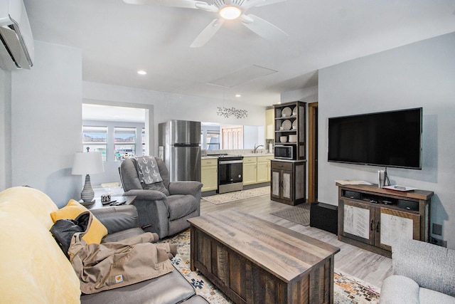 living area featuring a ceiling fan, attic access, recessed lighting, an AC wall unit, and light wood-type flooring