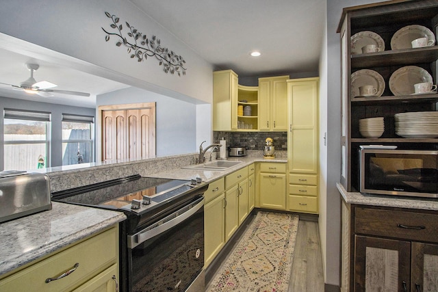 kitchen featuring open shelves, a sink, cream cabinetry, electric stove, and stainless steel microwave