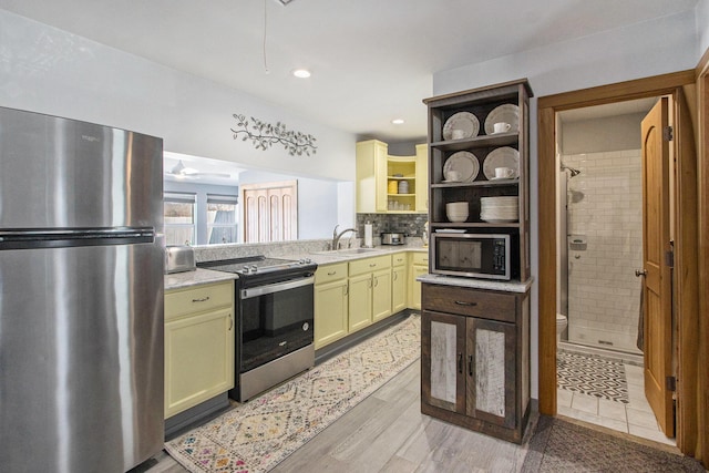 kitchen with a sink, open shelves, backsplash, stainless steel appliances, and light countertops