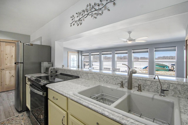 kitchen with black / electric stove, light wood-style flooring, ceiling fan, a sink, and light countertops