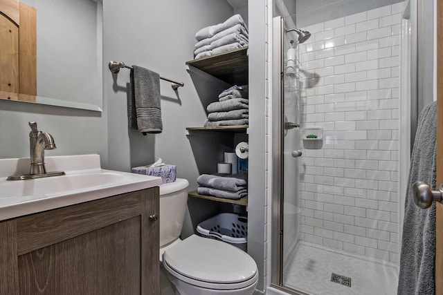 bathroom with a stall shower, toilet, and vanity