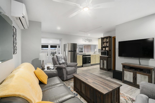 living area featuring a wall mounted air conditioner, attic access, a ceiling fan, and light wood finished floors