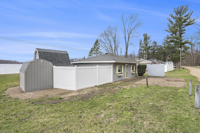 back of house with an outdoor structure, a storage shed, a yard, and fence