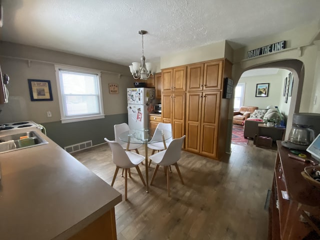 dining room with visible vents, a notable chandelier, a textured ceiling, arched walkways, and light wood-style floors