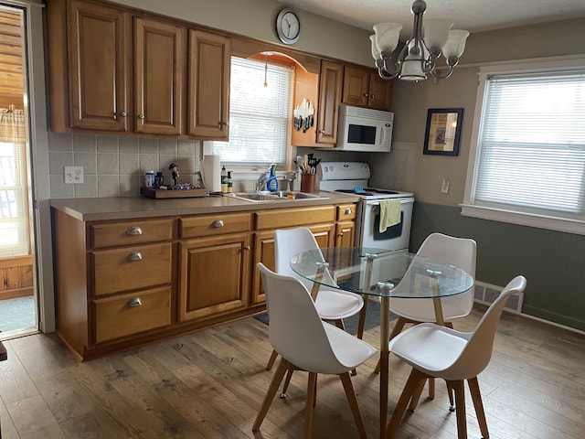 kitchen with white appliances, brown cabinets, and light wood-style flooring