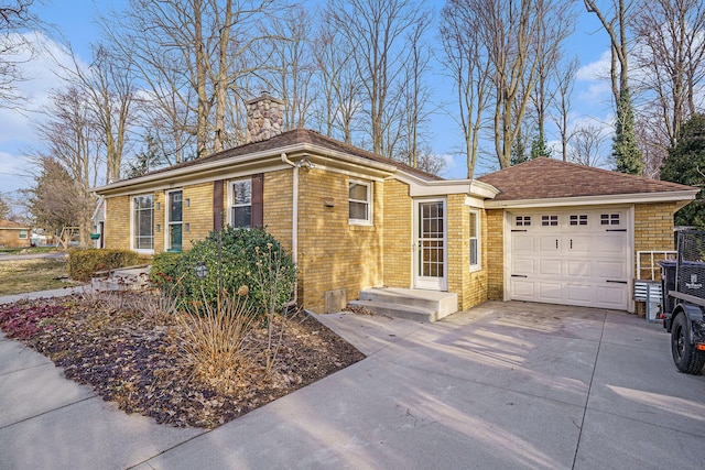 view of front of home featuring concrete driveway, brick siding, a garage, and a chimney