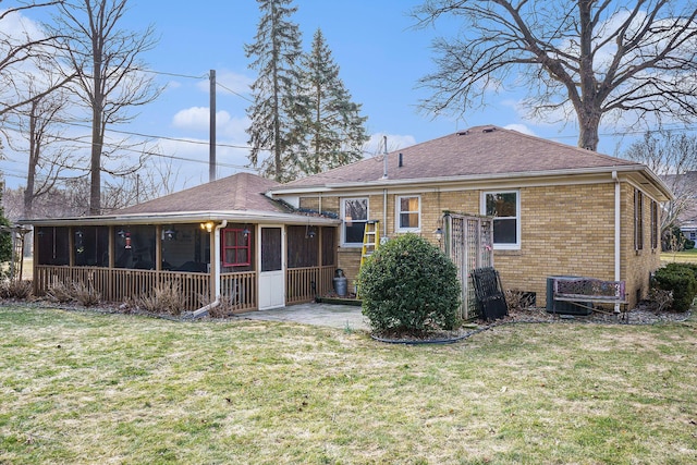 back of house featuring brick siding, a shingled roof, a yard, a sunroom, and a patio area