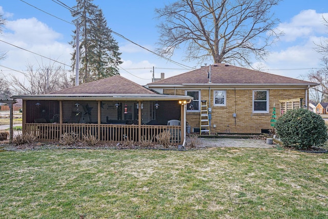 back of property featuring brick siding, roof with shingles, a yard, a sunroom, and a patio area