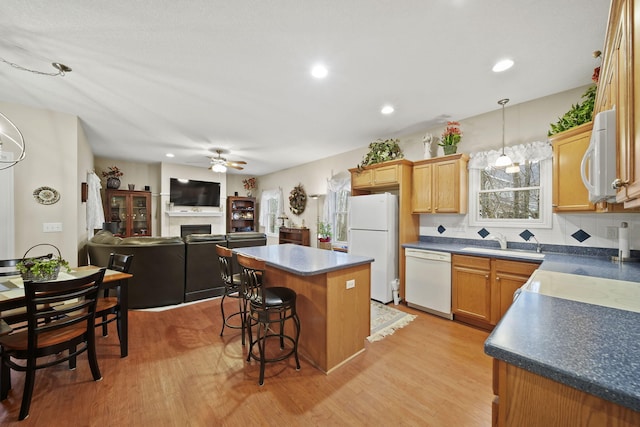 kitchen with dark countertops, white appliances, a kitchen island, and a fireplace