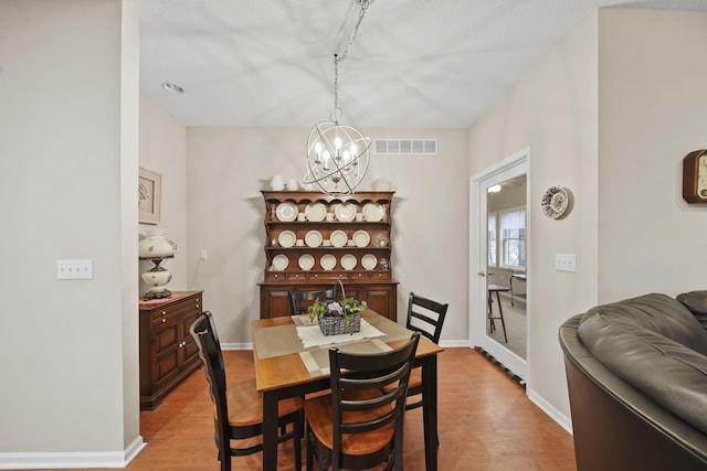 dining area with visible vents, baseboards, an inviting chandelier, and wood finished floors