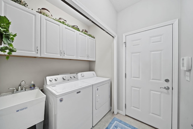 laundry area featuring washing machine and dryer, cabinet space, and a sink