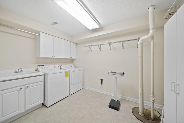 washroom with visible vents, washer and clothes dryer, light floors, cabinet space, and a sink