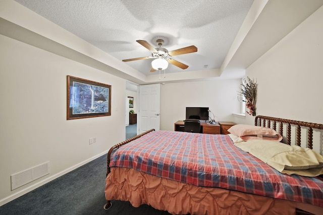 carpeted bedroom featuring visible vents, baseboards, a tray ceiling, a textured ceiling, and a ceiling fan