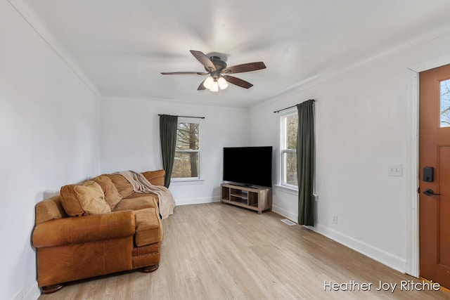 living room with light wood finished floors, plenty of natural light, a ceiling fan, and baseboards