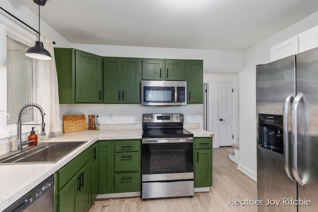 kitchen with a sink, stainless steel appliances, green cabinets, and light countertops