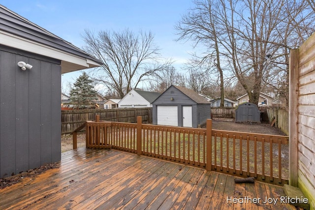 wooden deck with an outbuilding, a detached garage, a storage shed, and a fenced backyard