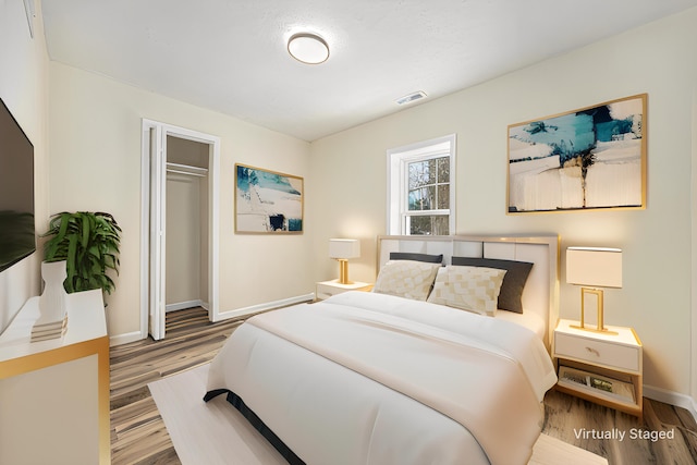 bedroom with a closet, visible vents, baseboards, and wood finished floors