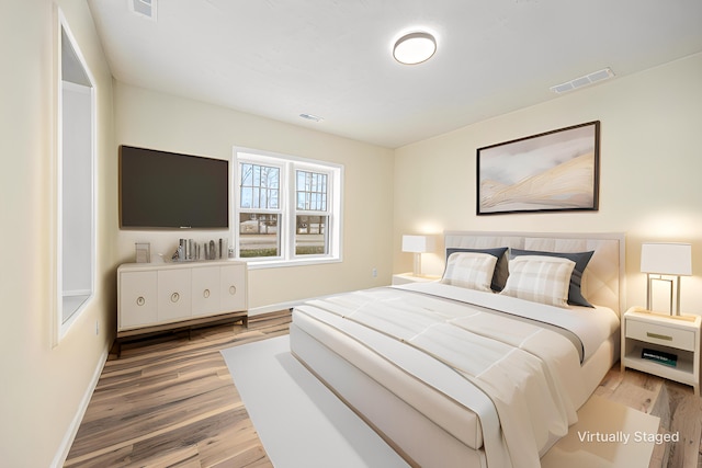 bedroom with visible vents, baseboards, and wood finished floors