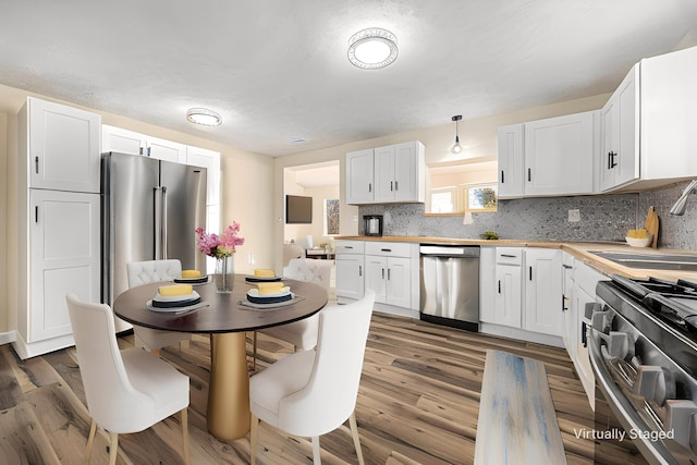 kitchen with a sink, stainless steel appliances, decorative backsplash, and white cabinetry